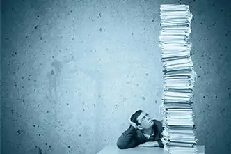 Young man with glasses in front of a huge pile of files