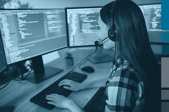 Female Portal Systems Support staff member with headset in front of screens.
