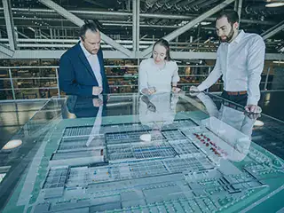 Mitarbeitende von io-consultants vor dem Modell eines Logistikzentrums: Mit einer elektronischen Lösung wird das Vertragsmanagement einfacher, schneller und effizienter.