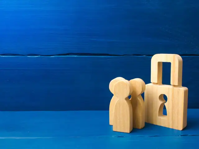 Ein Vorhängeschloß aus Holz und drei Holzfiguren.