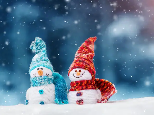 Zwei lächelnde Schneemänner mit Strickmütze und Schal.