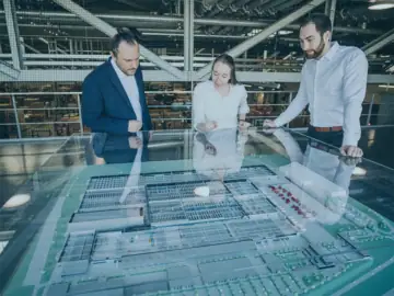 io-consultants staff in front of a model of a logistics centre: An electronic solution makes contract management simpler, faster and more efficient.
